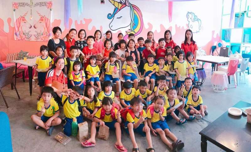 A large group of children and adults posing together after a DIY event