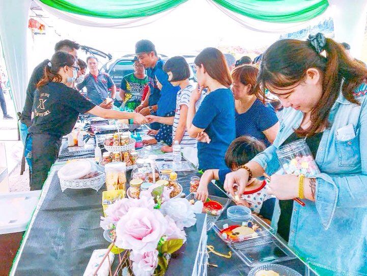 Visitors and crew at a busy Food DIY table with topping jars