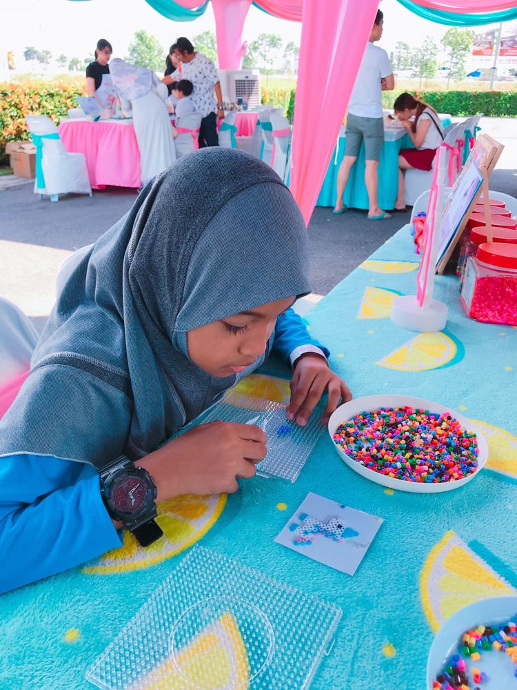 A child placing perler beads on a pegboard at a tent event