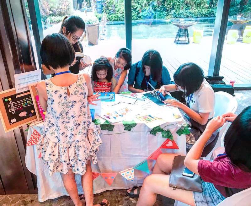 Children and adults making crafts at a decorated DIY activity table during an event